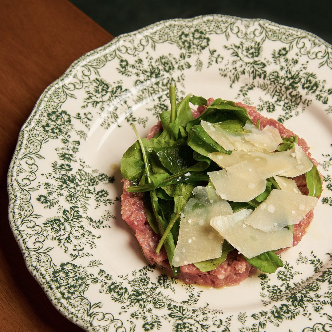 Lomito sin hormonas, bagna cuda emulsionado con yemas, arugula, aceite de hierbas, láminas de parmesano.